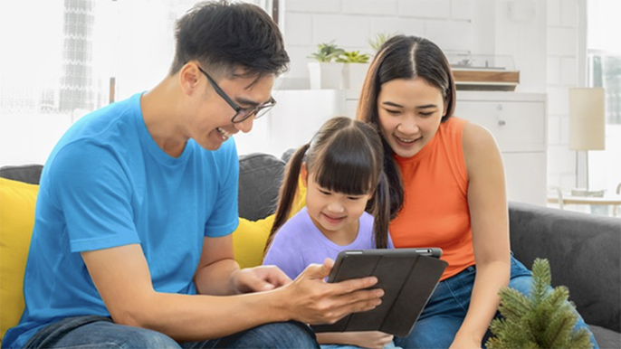 family of three smile and looking at a tablet 