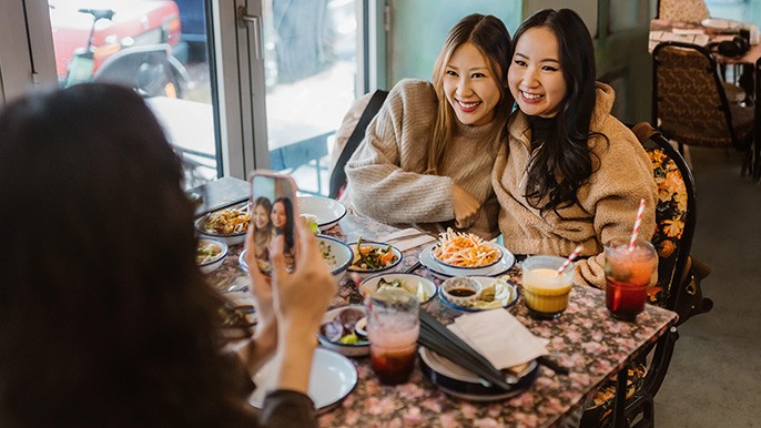 Deux femmes sont assises à une table sur laquelle se trouve une variété de nourriture et de boissons.